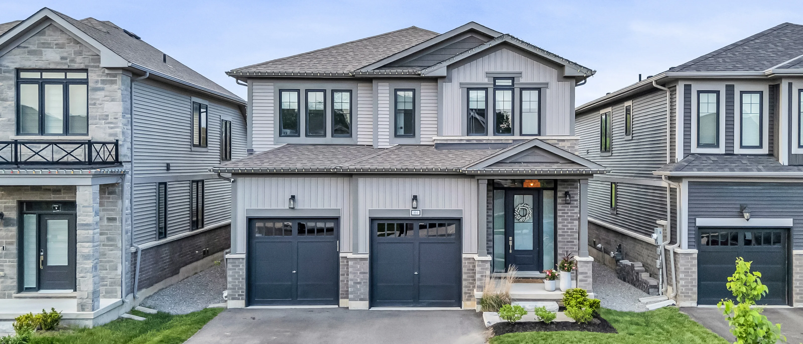Grey and stone new-build home exterior on a clear day