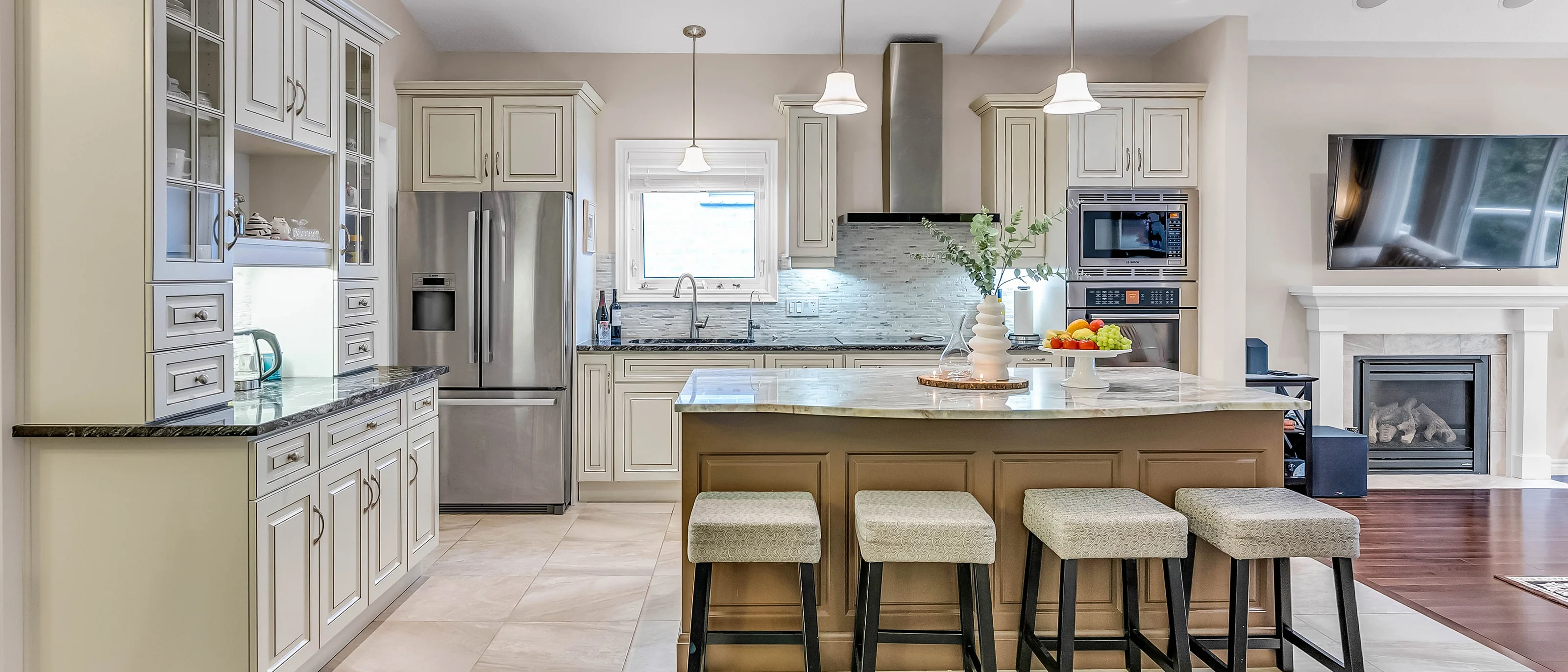 Cream kitchen with a large island, bar stools and a fireplace