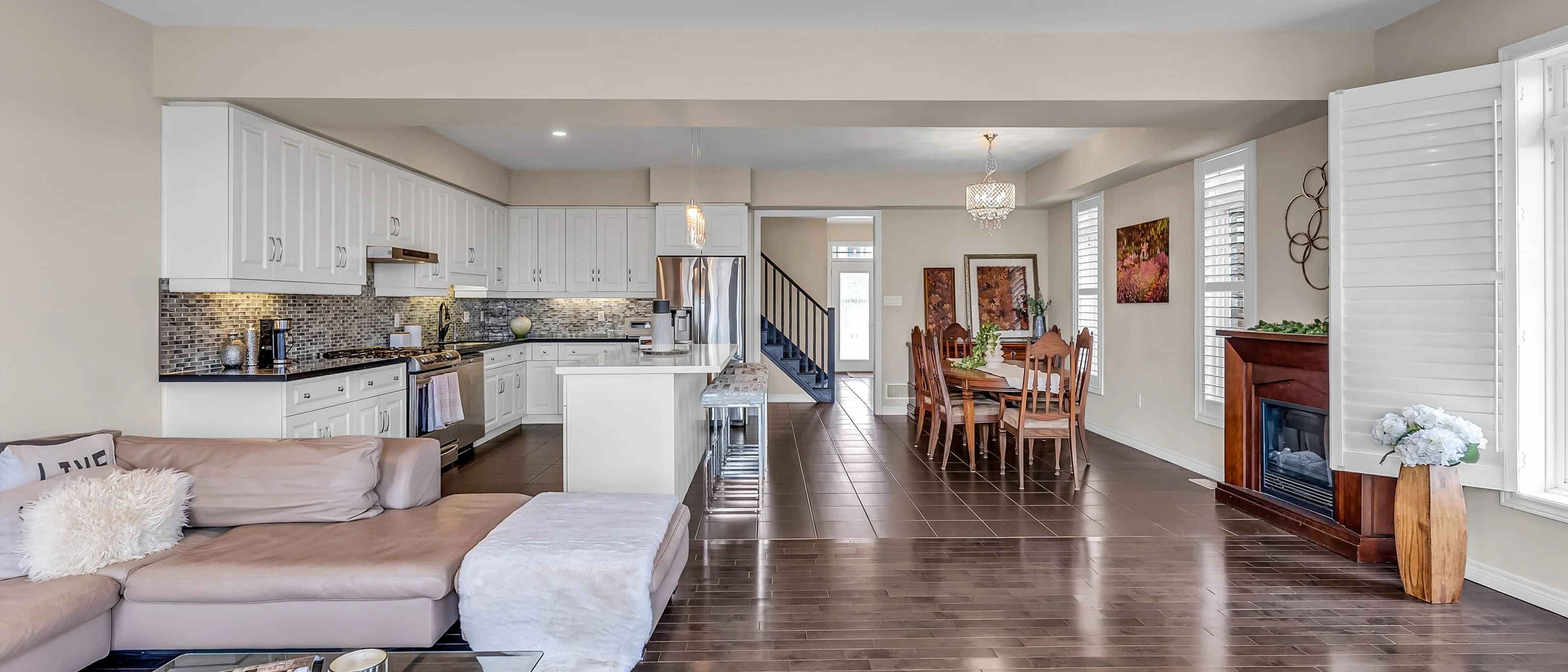 White kitchen opening onto a dining room and fireplace