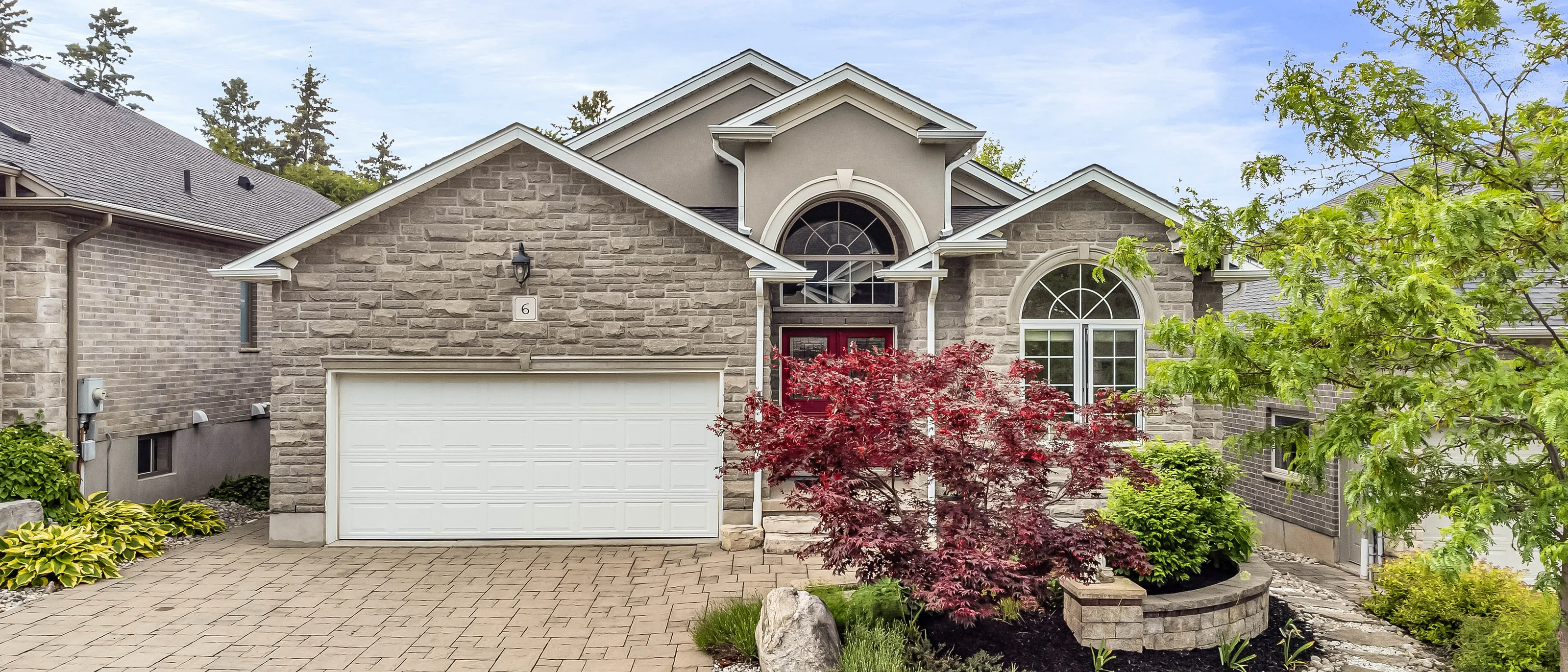 Stone-front bungalow with a landscaped garden and paved driveway