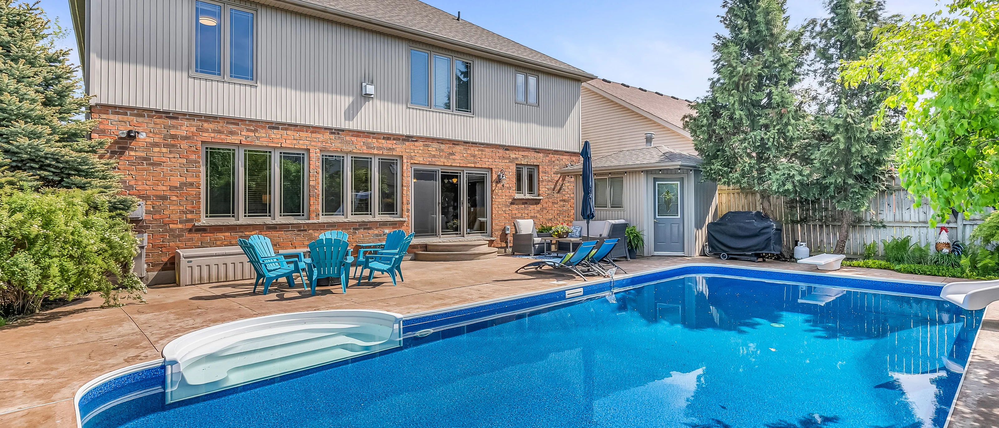 Backyard inground pool and patio behind a brick home