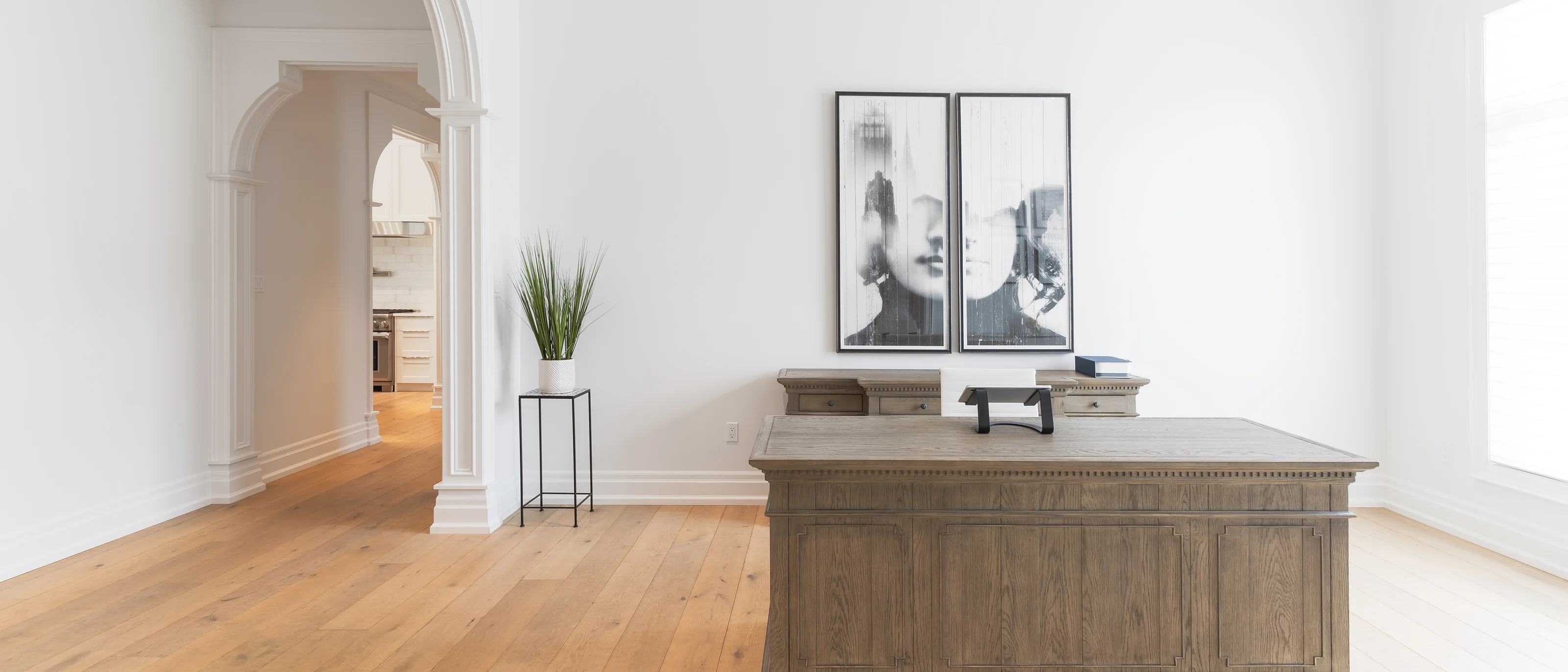 Bright empty entry hall with arched openings and oak floors