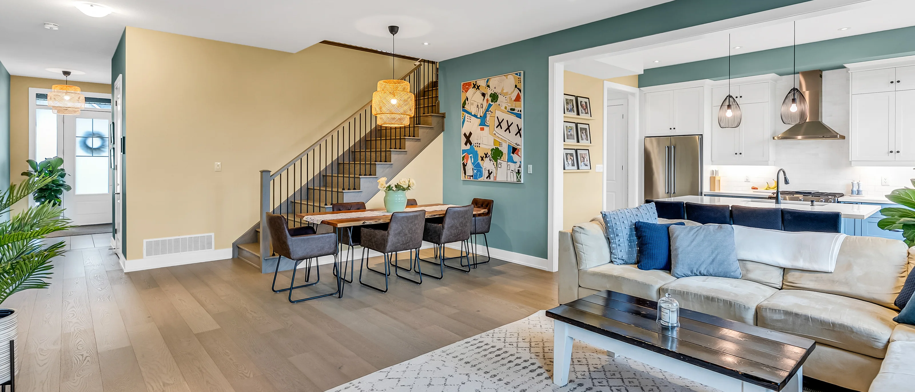 Dining and living space with teal walls and an open staircase